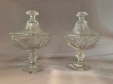 pair of clear glass covered dishes on pedestals on a table