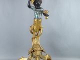 un vase doré et noir posé sur un socle, orné d'un oiseau