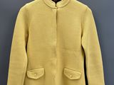 une veste jaune suspendue à un cintre devant un mur gris