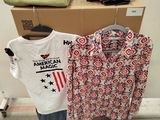 two shirts that are hanging on a rack in a room
