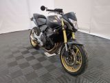une photo d'une moto noire et dorée garée sur un sol à damier