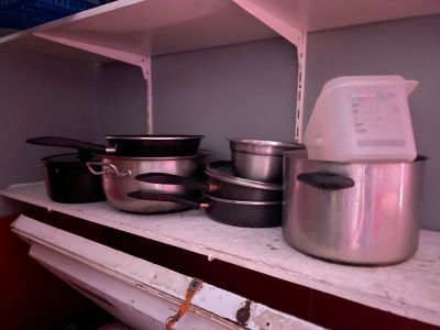 Plusieurs casseroles et poêles sont posées sur une étagère dans une cuisine