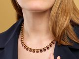 a woman in a black jacket and a gold necklace