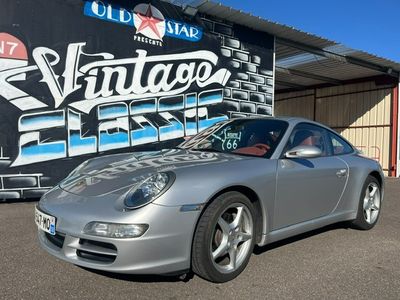 une Porsche argentée garée devant un immeuble orné d'une enseigne rétro