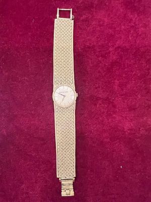 un gros plan d'une montre-bracelet posée sur une surface rouge