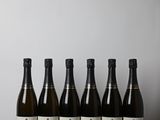 six bottles of wine lined up on a wooden table