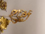 a close up of a gold brooch with flowers on it