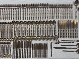a lot of silverware on a table with a white table cloth