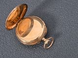 a gold pocket watch sitting on a blue surface
