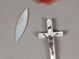 a cross and a knife on a table next to a red object