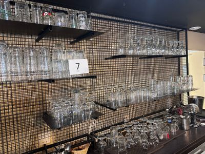 il y a beaucoup de verres vides sur les étagères du bar