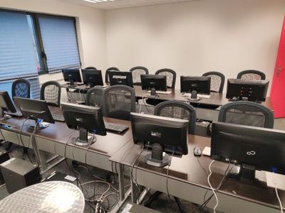 de nombreux ordinateurs posés sur les bureaux de cette pièce