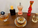 de nombreux parfums différents posés sur une table, avec un mur blanc en arrière-plan