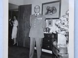 black and white photograph of a man in a military uniform standing in a living room