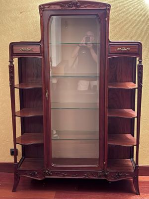 a display cabinet with a glass door in the corner