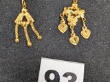 une paire de boucles d'oreilles en or représentant une femme tenant un sac à main