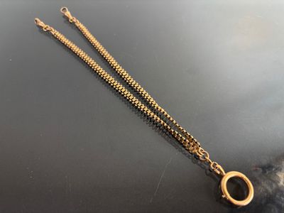 a close up of a gold chain with a ring on it