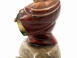 figurine of a man sitting on a rock with a hat on his head