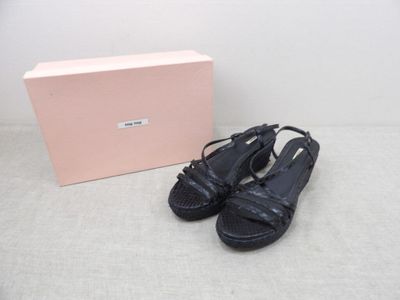 Les chaussures sont par terre, à côté d'une boîte rose.