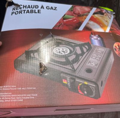 someone is holding a box with a stove in it on a table