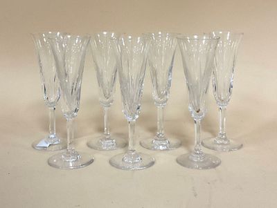 six verres à vin transparents sont alignés sur une surface blanche