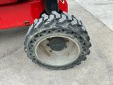 a red tractor with a big tire on the street