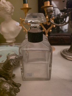 un flacon de parfum posé sur une table à côté d'une statue représentant un chat