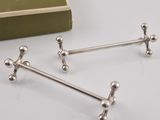three silver metal handles on a white surface next to a book