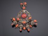 a close up of a broochee with coral and silver