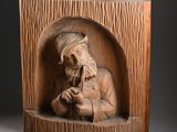 sculpture of an old man with a beard and a hat sitting in a wooden box