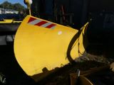 a large yellow snow plow sitting in the grass