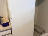a white refrigerator in the corner of a small kitchen