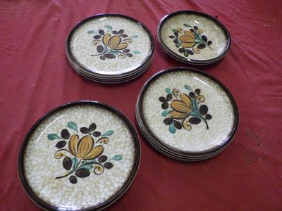 four plates with flowers on them are sitting on a red cloth