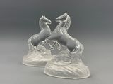 une paire de figurines de chevaux en verre transparent posées sur un rocher