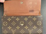 a close up of a person ' s hand holding a louis vuitton wallet