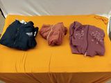 trois vestes posées sur une table jaune, sur fond blanc