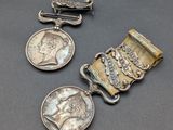 trois médailles d'argent et une agrafe sur un fond gris