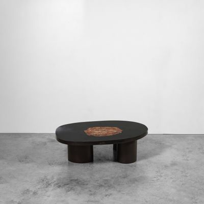 une table basse noire avec un piètement en bois et un plateau circulaire