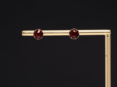 a pair of gold and garnetite earrings on a black background