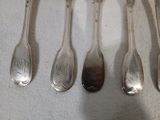six cuillères en argent sont alignées sur une table