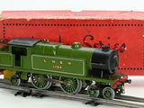 a small green train on the tracks next to a red box