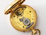 a close up of a pocket watch on a white surface