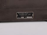 a brown suitcase sitting on a white surface with a tag on it