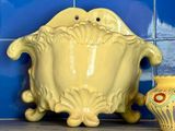 a yellow vase sitting on a shelf next to a blue tiled wall