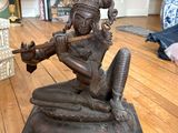 une statue représentant une femme jouant de la flûte sur un parquet