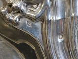 a close up of a silver clock with a bird on it