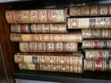 de nombreux livres anciens empilés sur une étagère dans une bibliothèque