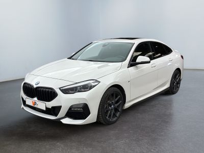 une BMW M140i break sportive blanche garée dans une pièce blanche