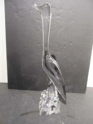 a glass sculpture of a bird sitting on a rock