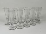 six clear wine glasses lined up in a row on a white surface